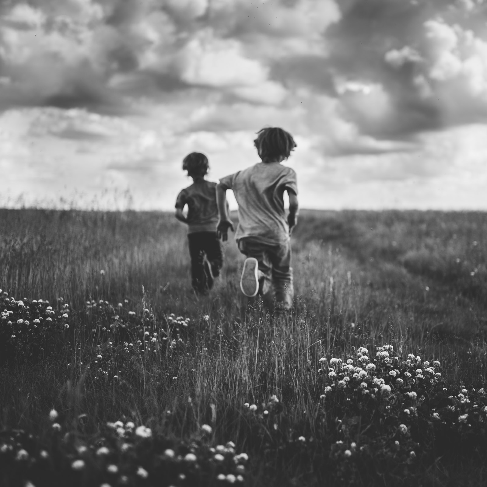 black-and-white-picture-of-boys-running-in-a-field-by-Andrea-Brooke-Photography